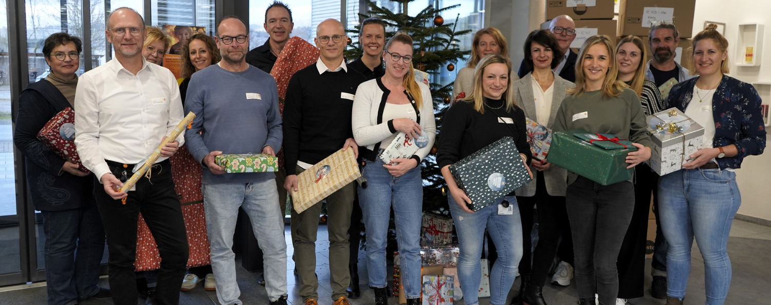 Wunschaum Geschenke Übergabe bei Testo Industrial Services Mitarbeitende der Testo SE & Co KgaA und Testo Industrial Services stehen vor dem Weihnachtsbaum und haben Geschenke in der Hand