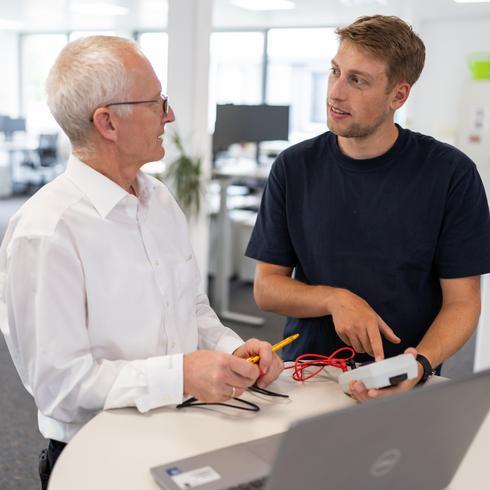 Two men are apeaking with each other about a measurement device