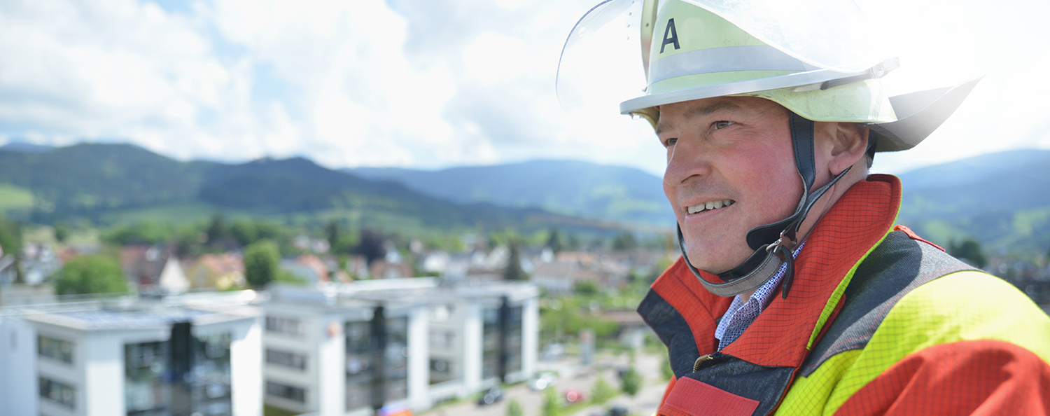 Ein Testo-Mitarbeiter in Feuerwehruniform mit Testo im Hintergrund.