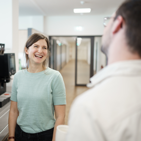 Lächelnde Testo Industrial Services Mitarbeiterin neben Kaffeemaschine