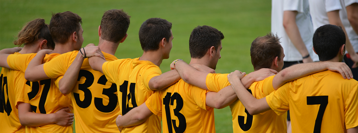 Teamplayer in Beruf und Freizeit Testo-Mitarbeiter stehen im Fußballtrikot zusammen und halten sich in den Armen.