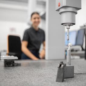 An einer KMG wir ein Werkstück von einer Frau geprüft