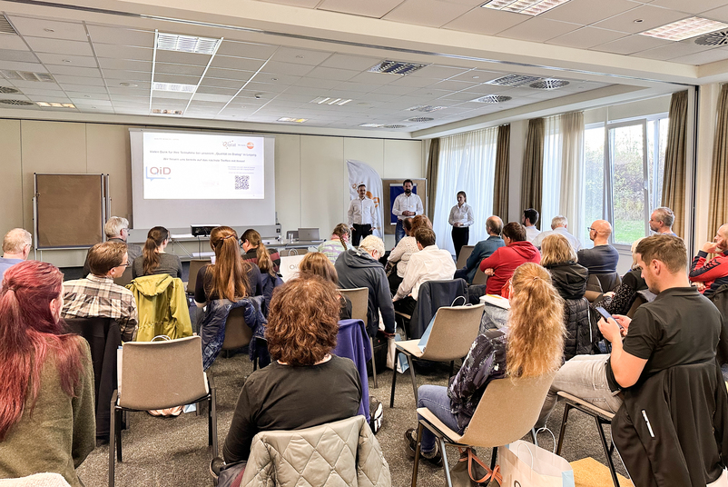 Teilnehmende der Veranstaltung Qualität im Dialog in Leipzig hören bei einem Vortrag zu