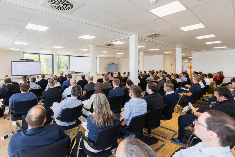 Symposium Kalibrierung & Prüfmittelmanagement 2026 Zahlreiche Teilnehmende sitzen in einem Veranstaltungsraum und verfolgen einen Fachvortrag. Mehrere Bildschirme zeigen die Präsentation der Referierenden.