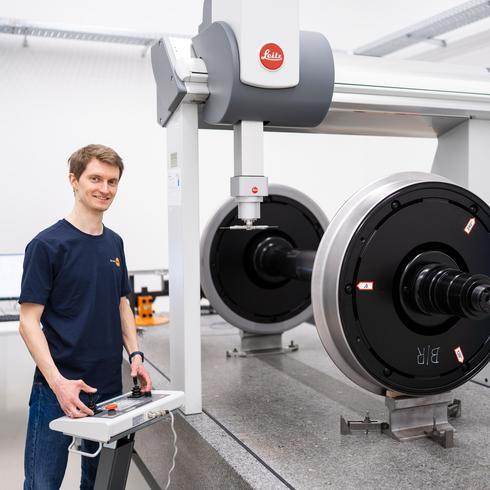 Person im Labor neben einem Radsatz