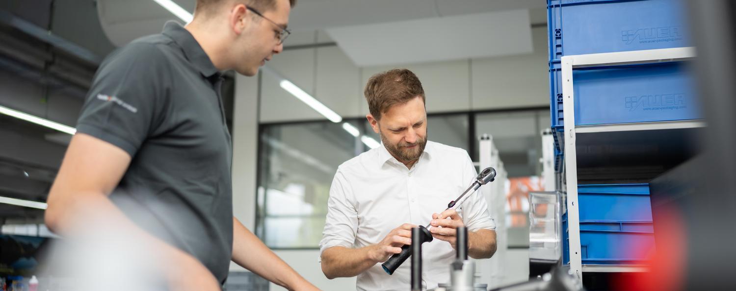 Two men are calibrating a torque wrench.