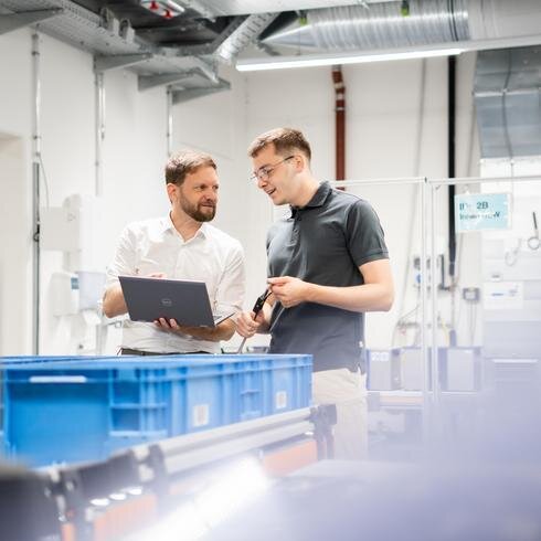 Zwei Männer in einem Labor sehen auf einen Laptop