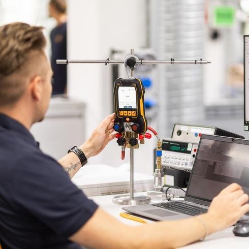 Druck-Fibel: Messtechnik und Kalibrierung Rückansicht eines Mannes der ein Druckmessgerät kalibriert