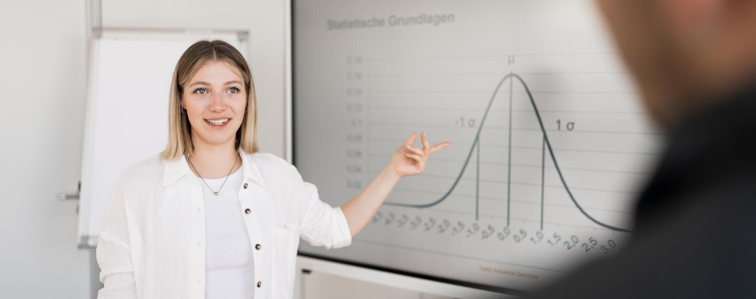 Seminar: Grundlagen der Statistik (fast) ohne Formeln Frau zeigt etwas auf einem Bildschirm.