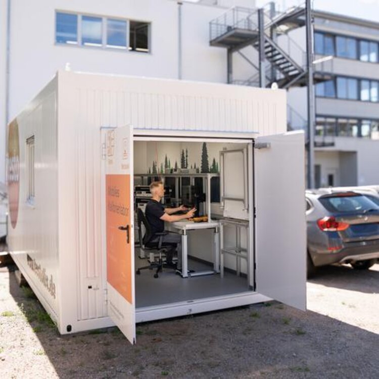 Calibration in a mobile laboratory directly at your site Person sitting in a mobile calibration laboratory container