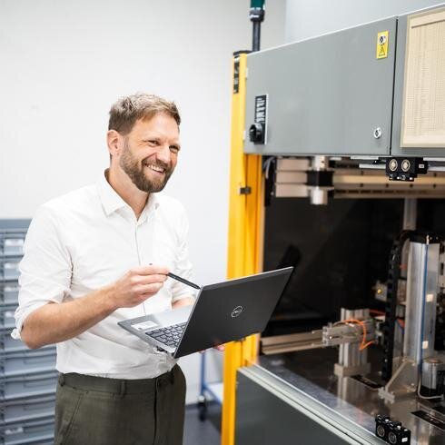 Mann mit Laptop steht vor einen Drehmomentprüfstand